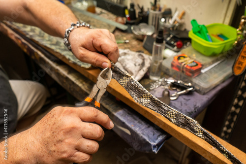 Latin saddler working on handicrafts, belts, bags and wallets on snakeskin leather.