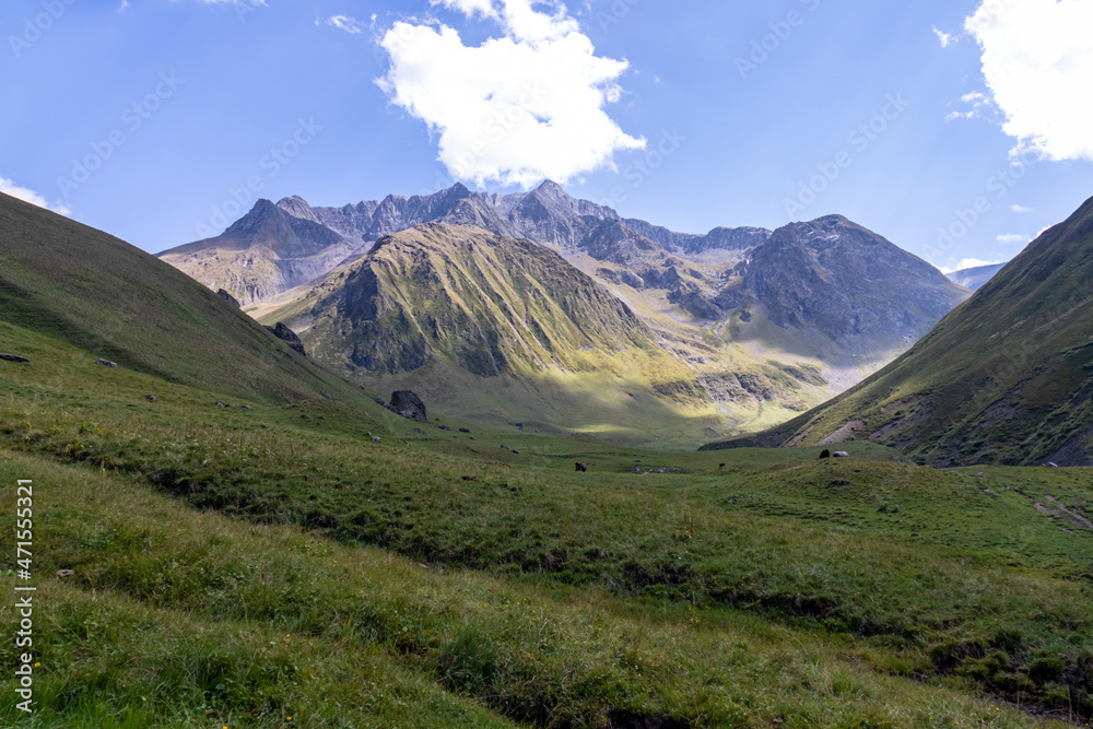 Obraz premium A panoramic view on the high mountain peaks of the Chaukhi massif in the Greater Caucasus Mountain Range in Georgia, Kazbegi Region. A valley with lush green pastures. Wanderlust. Remote location.