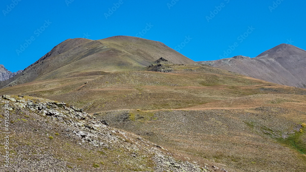 A panoramic view on the green hills and sharp ridges of the mountain peaks of the Chaukhi massif in the Greater Caucasus Mountain Range in Georgia, Kazbegi Region. Wanderlust. Clear Sky. Hike