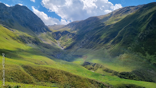 A  green grassland in the Greater Caucasus Mountain Range in Georgia  Kazbegi Region. The surrounding mountains and hills are green and soft. Tranquility. Highlands. Clear Sky.