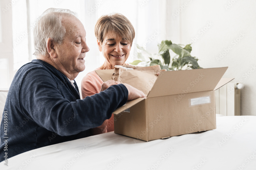 Happy senior couple unpacking parcel box from online delivery service - Focus on woman face Happy senior couple unpacking parcel box from online delivery service - Focus on woman face