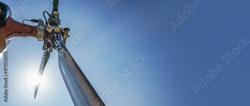 Looking up military helicopter rear rotor and blades, bright sun and sky back...