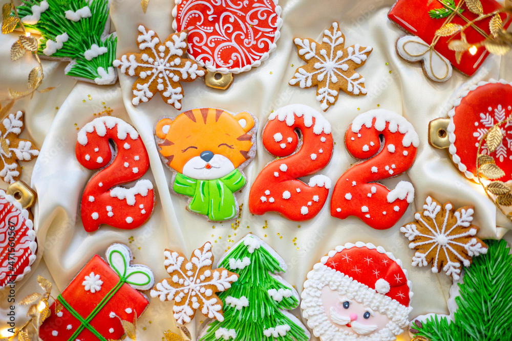 Banner for Christmas and New Year gingerbread cookies numbers 2022, snowflakes, Santa hat, Christmas trees, garlands on white silk fabric background, gingerbread tiger symbol Chinese zodiac calendar