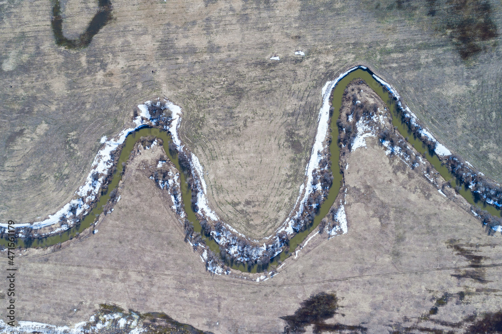 Top view of river running through bare farmland
