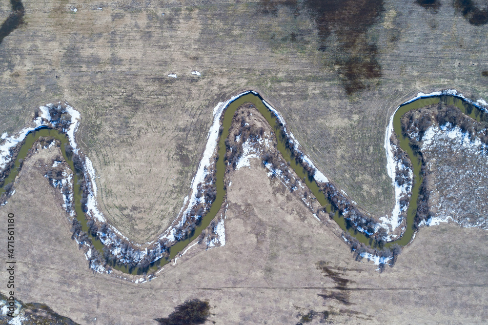 Top view of river running through bare farmland