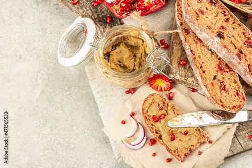 Fresh homemade chicken liver pate or paste in a glass jar with baguette slices on the serving board