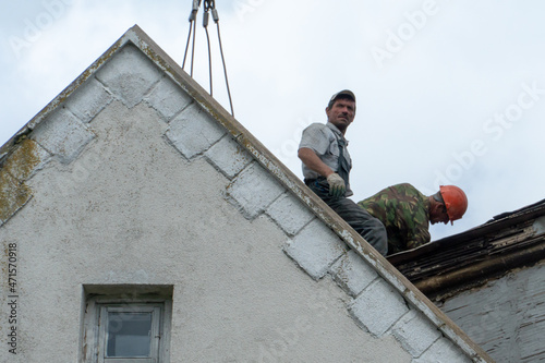 Repair of the roof of a beautiful old building in the city center. High-altitude work involves a risk to life. Workers are repairing the roof  replacing tiles  eliminating leaks.