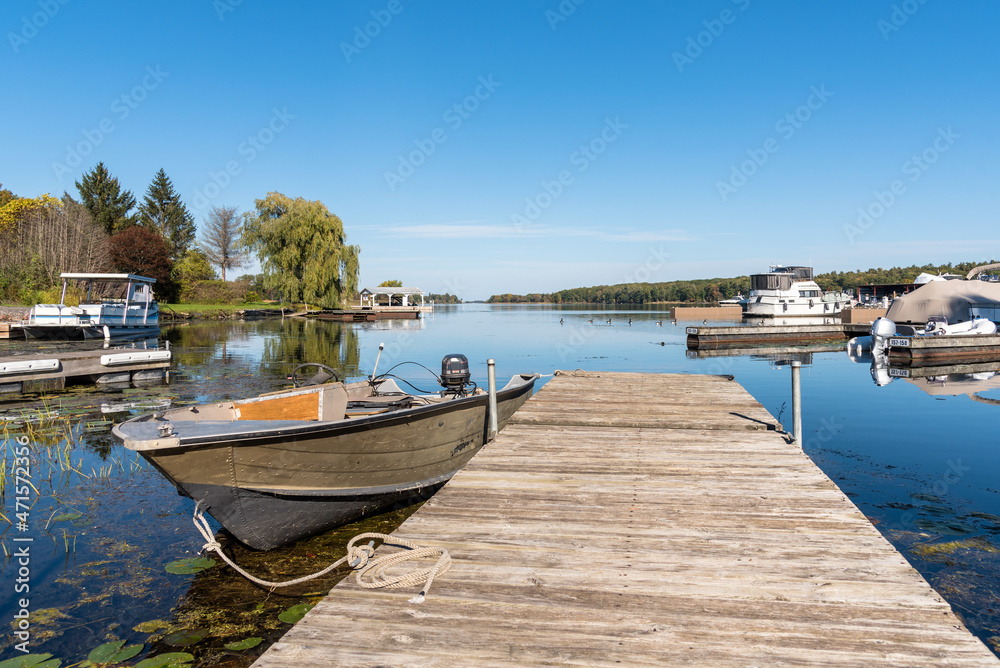 Motorboat moored to a weathered wooden jetty in a river harbour on a clear autumn day. Tranquil scene. Motorboat moored to a weathered wooden jetty in a river harbour on a clear autumn day. Tranquil scene.