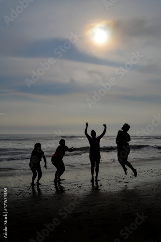Silhouette of 4 women jumping on a beach at sunset