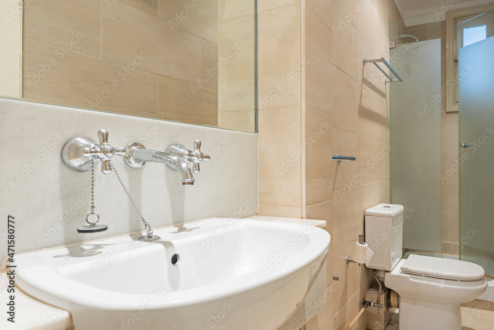 Fototapeta premium Sink with individual taps for hot and cold water in a bathroom with marble walls