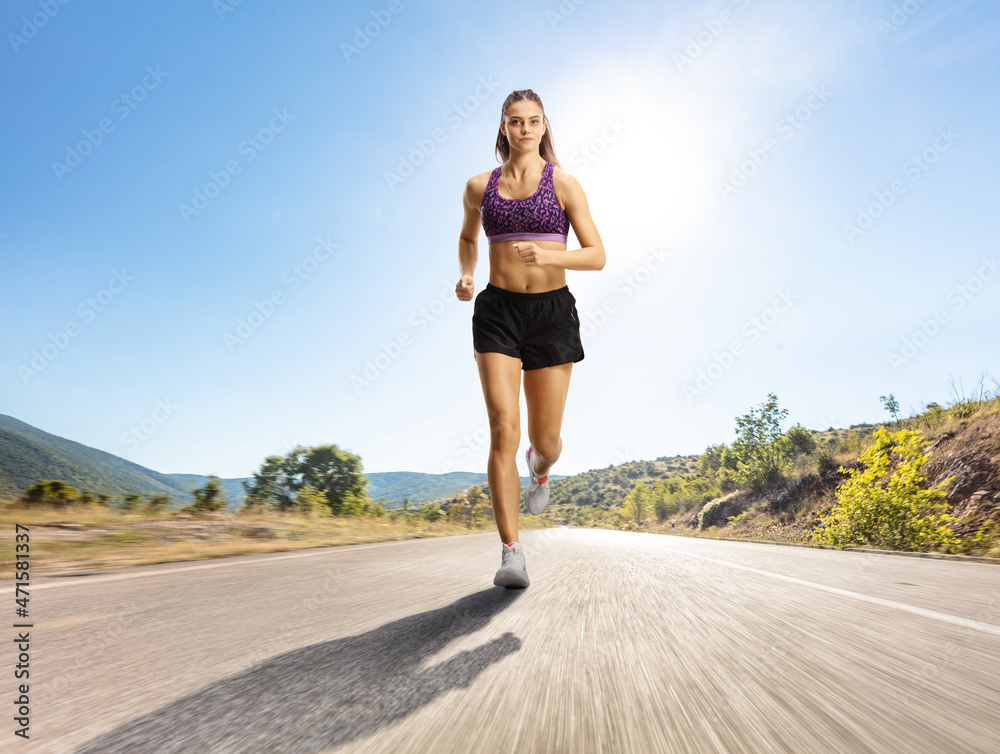 Female wearing crop top and shorts and running on an open road