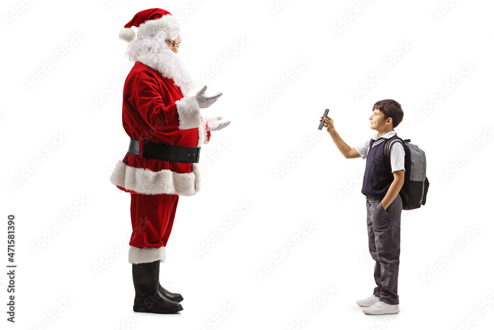 Full length profile shot of a boy in a school uniform showing a smartphone to santa claus Full length profile shot of a boy in a school uniform showing a smartphone to santa claus