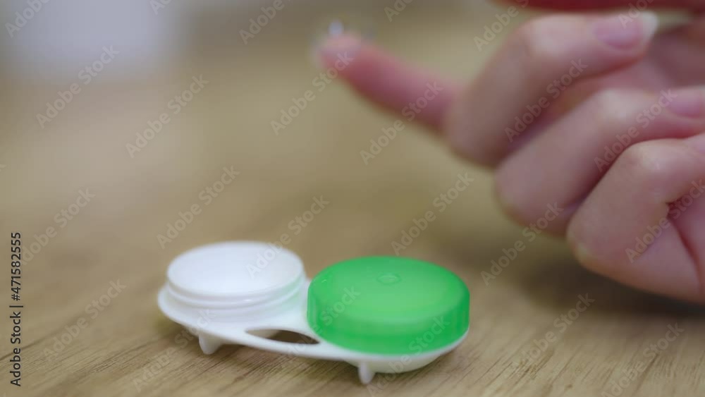 a woman's hand takes contact lenses from the container for one finger. a woman's hand takes contact lenses from the container for one finger.
