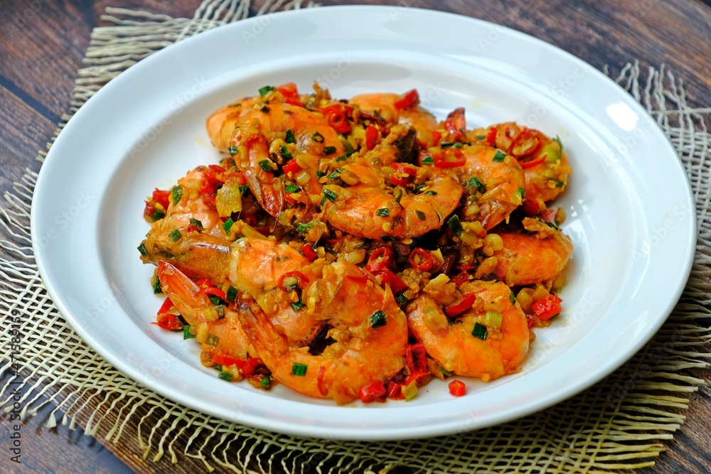 Stir fried prawns with chilli garlic and salt in white plate on wooden table. Thai seafood. Stir fried prawns with chilli garlic and salt in white plate on wooden table. Thai seafood.