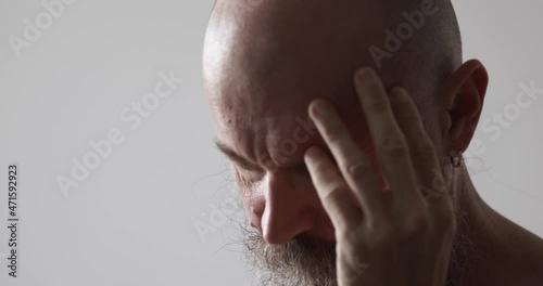 Pensive stressed mid adult man looking down, scratching head, might have some headache
