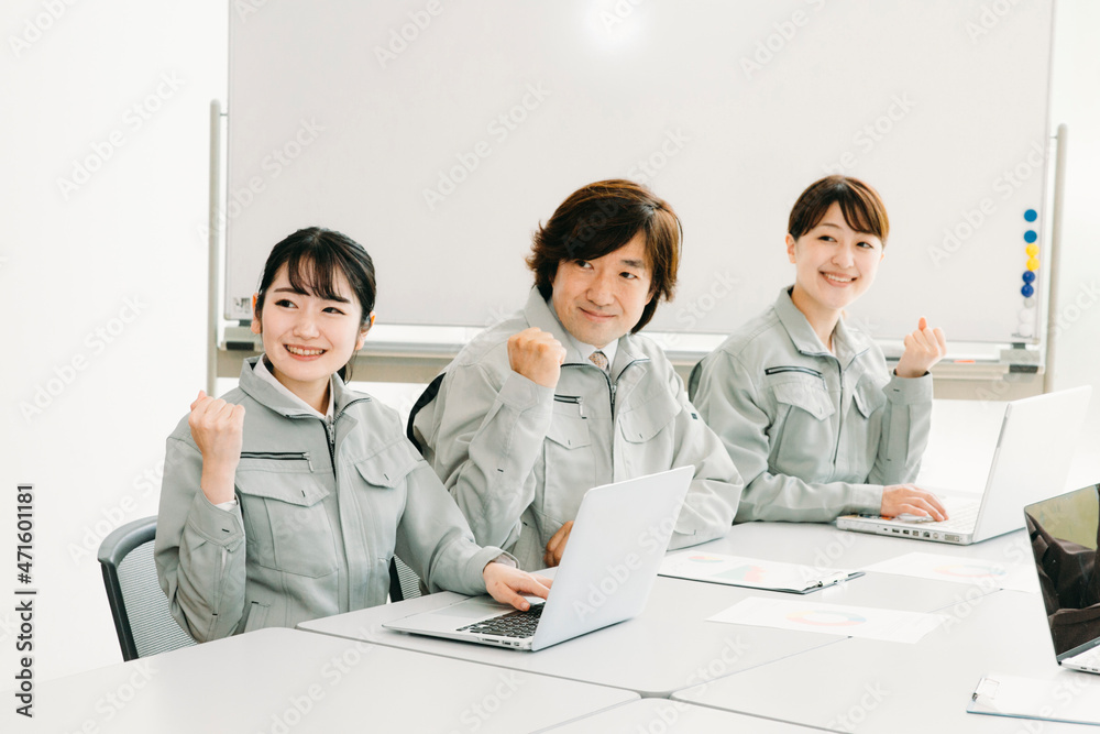 会議をする作業着をきた会社員(ガッツポーズ・3人)
会議をする作業着をきた会社員(ガッツポーズ・3人)