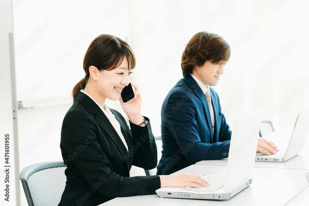 仕事するスーツ姿の女性（電話・2人）
