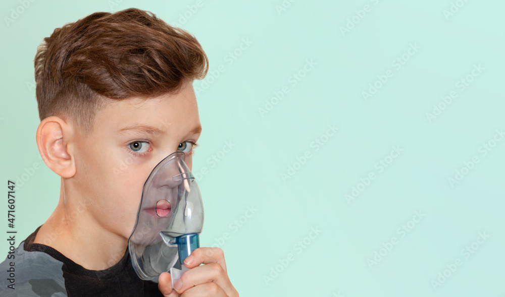 the boy holds an inhalation mask to his face