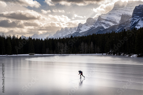 Fototapeta Naklejka Na Ścianę i Meble -  A person ice skating on a frozen mountain lake in Banff National Park