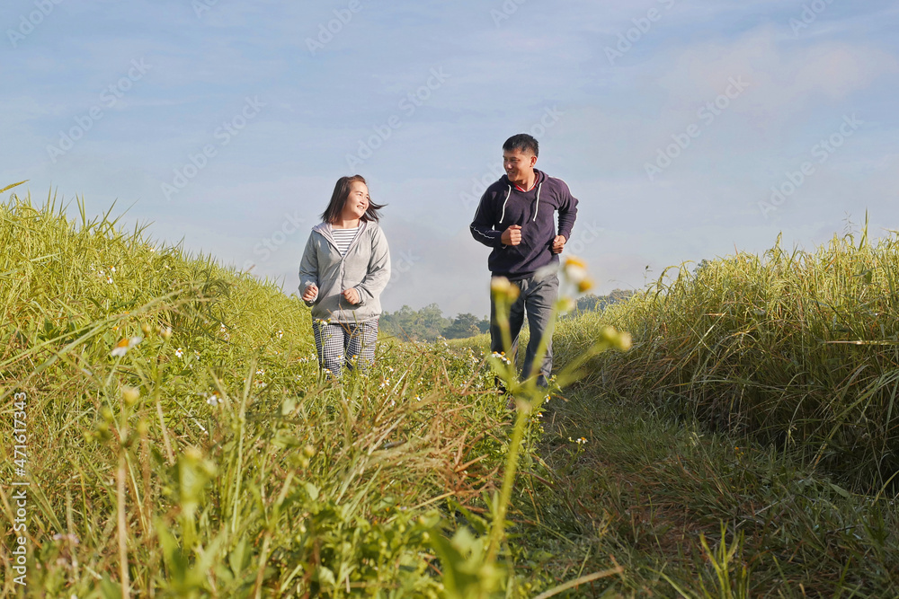 Asian couple jogging together, outdoor morning run in nature trail organic rice paddy field. Healthy lifestyles and sustainability concepts. Asian couple jogging together, outdoor morning run in nature trail organic rice paddy field. Healthy lifestyles and sustainability concepts.