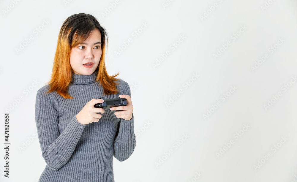 Portrait closeup studio shot of Asian young teen female model gamer in gray turtleneck dress standing smiling holding 3d video game dualshock console joystick in hands playing on white background Portrait closeup studio shot of Asian young teen female model gamer in gray turtleneck dress standing smiling holding 3d video game dualshock console joystick in hands playing on white background
