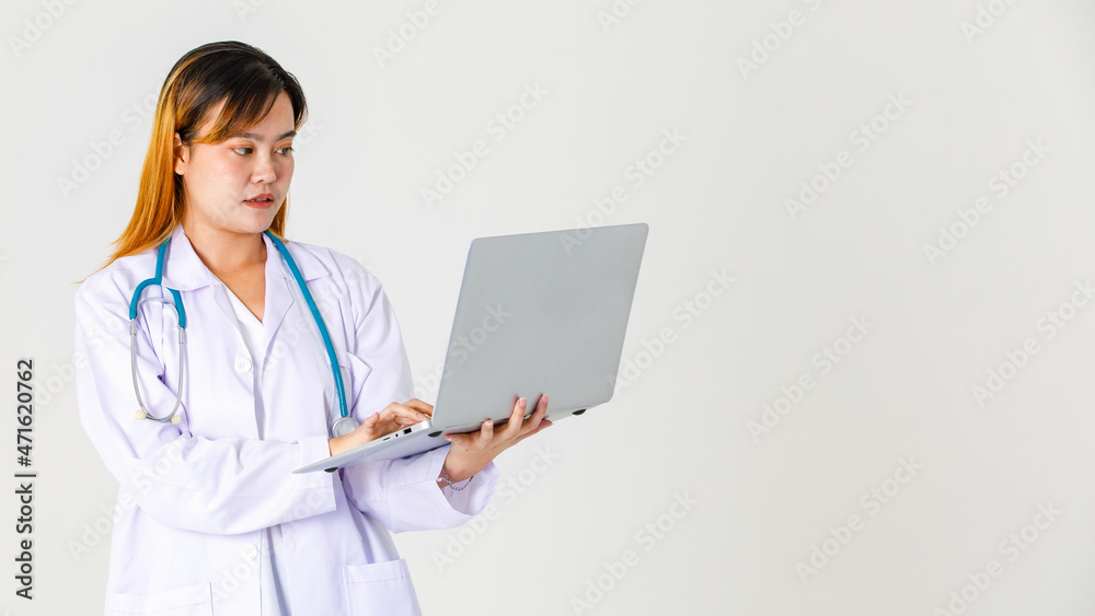 Studio shot of Asian successful professional confident female clinical doctor in lab coat uniform hanging stethoscope around neck standing working typing holding laptop computer on white background Studio shot of Asian successful professional confident female clinical doctor in lab coat uniform hanging stethoscope around neck standing working typing holding laptop computer on white background