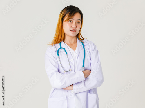 Portrait studio shot of Asian young successful professional confident dyed hair female doctor in lab coat hanging stethoscope around neck standing crossed arms look at camera on white background