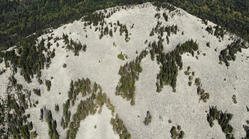 Aerial view of rocky mountain range. Panoramic view of the green dense forest at the foot of the hill. Mountains can be seen in the distance in the fog. Drone videoshooting photo