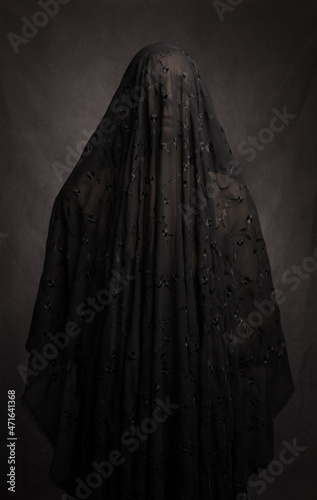 Fine art portrait of naked woman covered by lace veil in dark painterely studio setting