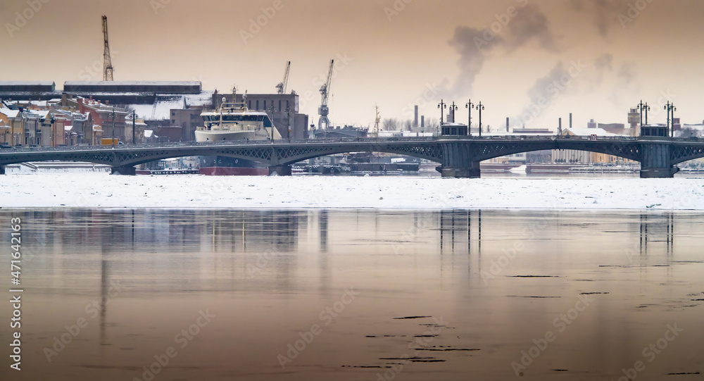 The panoramic image of the winter city Saint-Petersburg with picturesque reflection on water at sunset, big ship moored near Blagoveshchensky bridge, English embankment