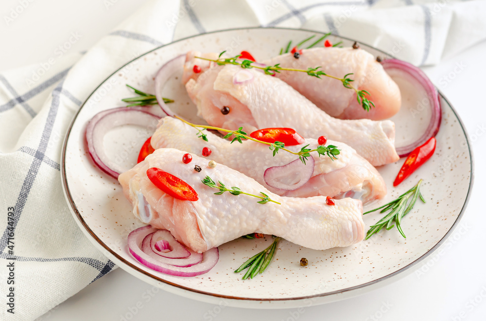 White dish with spicy marinated chicken legs or drumsticks. Raw meat and cooking concept. White dish with spicy marinated chicken legs or drumsticks. Raw meat and cooking concept.