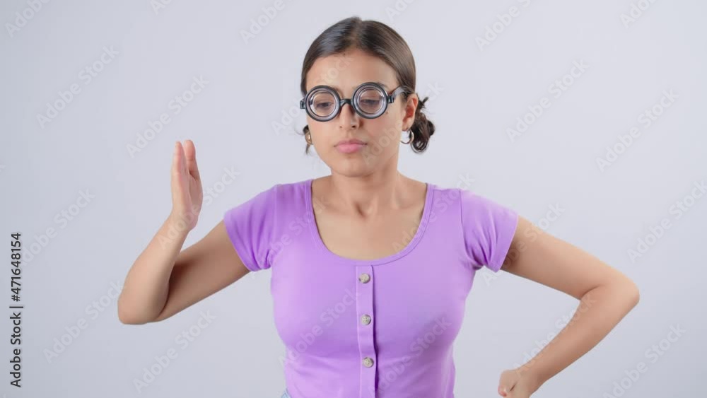 Slow motion shot of a young modern Indian Asian retro or old fashioned nerd female wearing strong thick eyeglasses dancing or moving hands in robotic style isolated on a white background screen. 