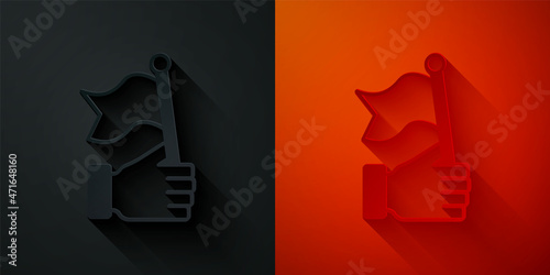 Paper cut Hand holding flag icon isolated on black and red background. Victory, winning and conquer adversity concept. Paper art style. Vector
