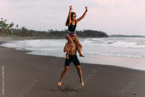A happy couple is having fun on the seashore. A beautiful couple fooling around on the beach of the paradise island of Bali. The couple rejoices at the cancellation of the lockdown. Vacation at sea