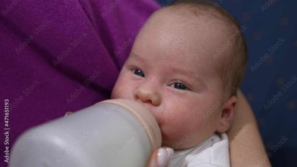 Adorable newborn baby being fed from the bottle. Mother holding her child in arms and feeding it from the bottle. Close up. Adorable newborn baby being fed from the bottle. Mother holding her child in arms and feeding it from the bottle. Close up.