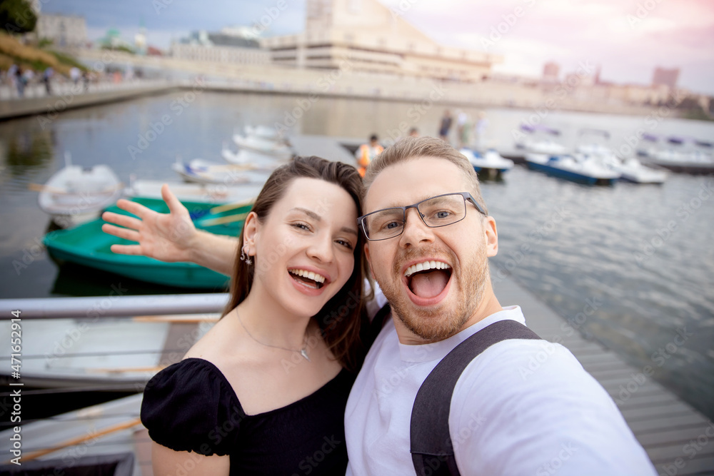 Happy couple man and woman traveler makes selfie photo on background of catamarans parking sunlight. Concept Turkey travel walk on sea and lake