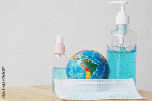 Globe world model, Surgical mask, Alcohol gel and spray on the wooden table for selective focus and blurred background. COVID-19 crisis in the world.Outbreak of Coronavirus and influenza.