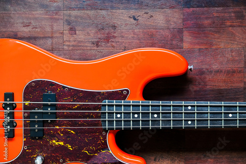 Canvas Print orange electric bass guitar on wood background with copy space