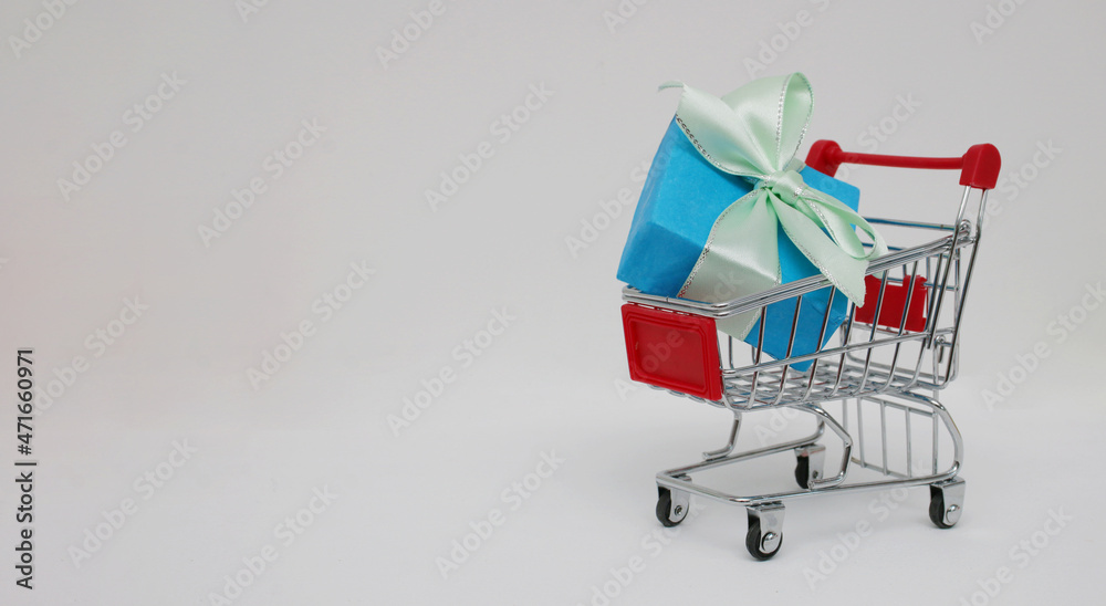 Christmas decorative gift blue box in a mini shopping trolley on a white background.