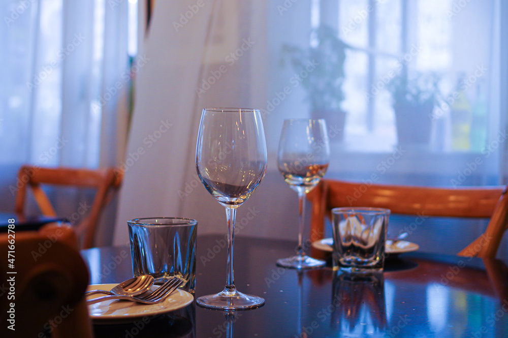 table setting in empty restaurant with clean wine glasses and cutlery on black table	