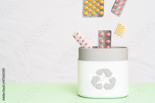 Full of expired pills and medicines in the trash bin with recycling symbol. Waste management concept.