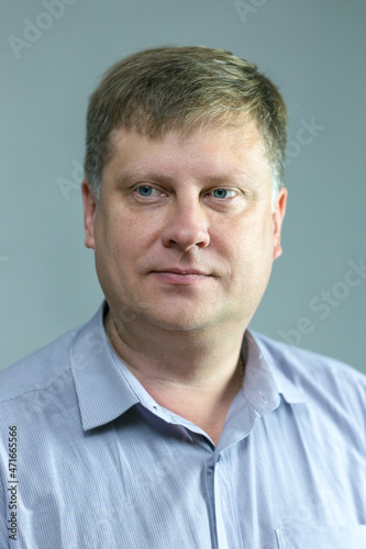 Portrait of a serious adult male blond 40 years old with a blue shirt on a black background.