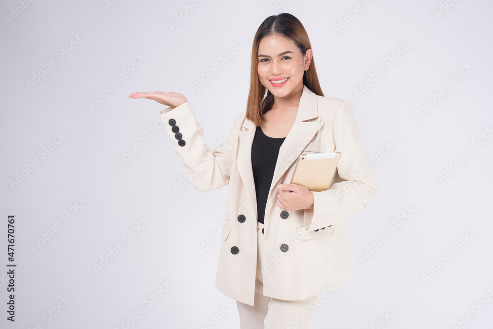 Young beautiful businesswoman in suit holding tablet over white Studio background. Young beautiful businesswoman in suit holding tablet over white Studio background.