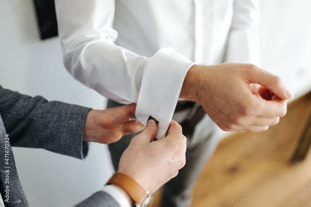 Best man helping the groom to put on cufflinks 