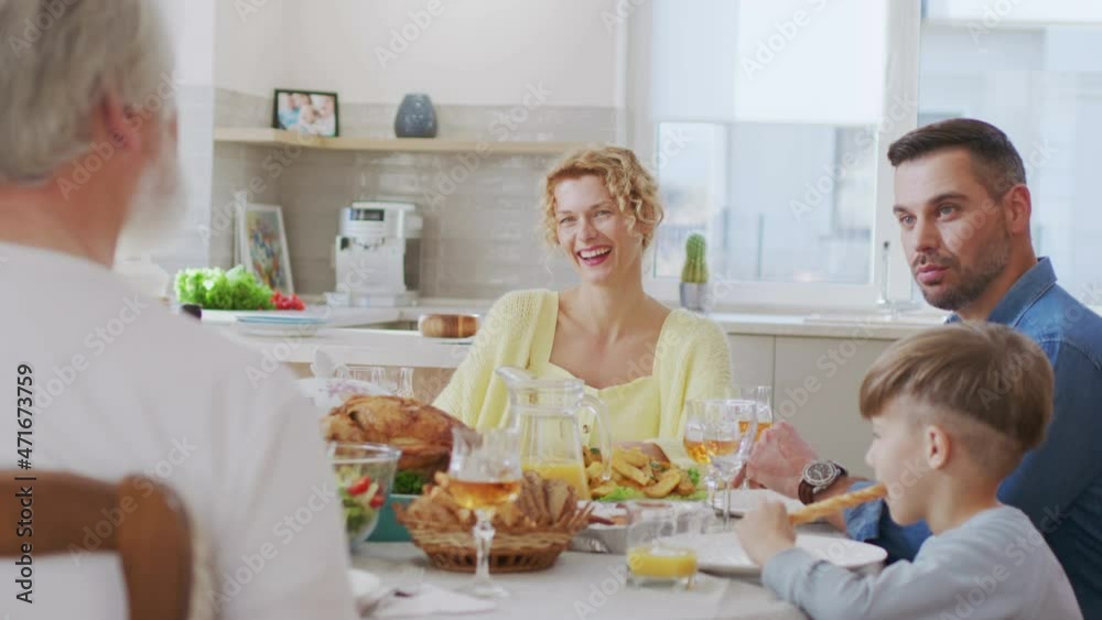 Caucasian family gathering together and chatting. Happy man telling something to his senior father while sitting at the table and spending time with family