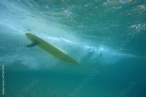 surfboard with a fin going through the water. Photographed from underwater