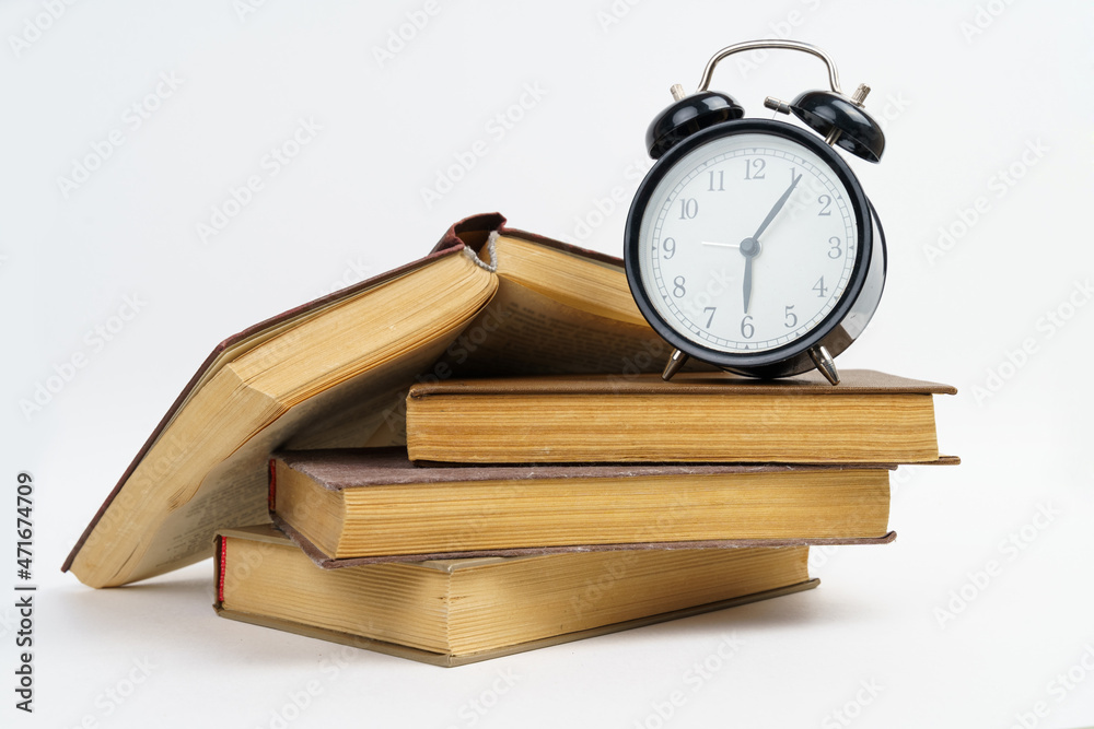 Books and an alarm clock lie on a white background.