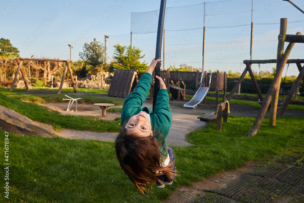 school child hanging from a rope in an incredible playground with sunset colors