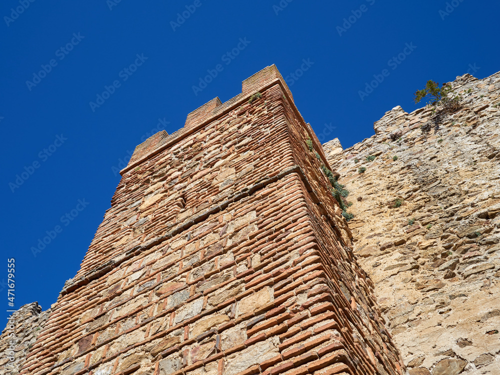 Close-up of the defensive stone city wall of the medieval village Buitrago del Lozoya with a brick tower. Madrid, Spain.