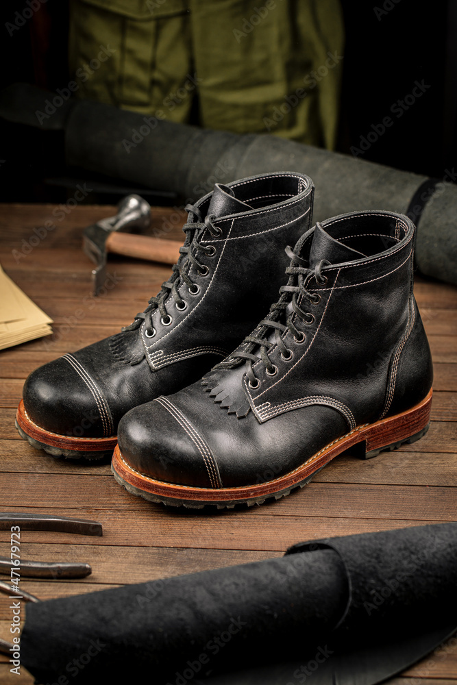 Hand crafted black leather high boots on wooden background Hand crafted black leather high boots on wooden background
